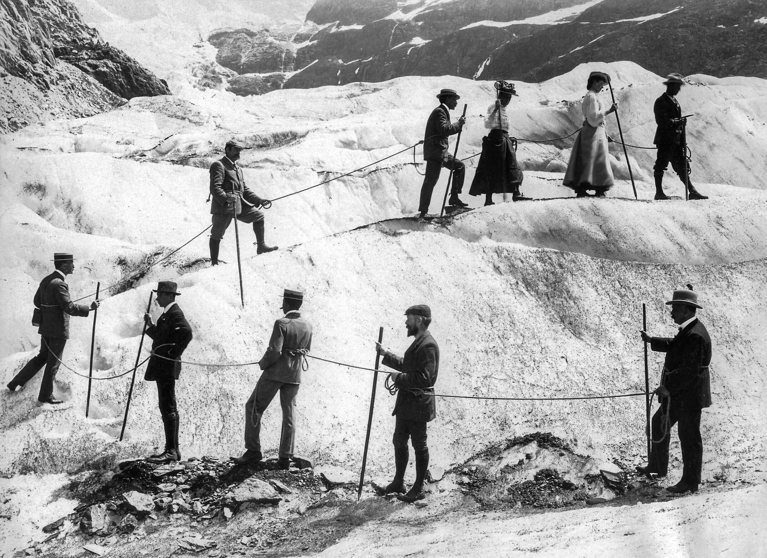 Un grupo de personas, unidas por una cuerda avanzan sobre la nieve en un glaciar.