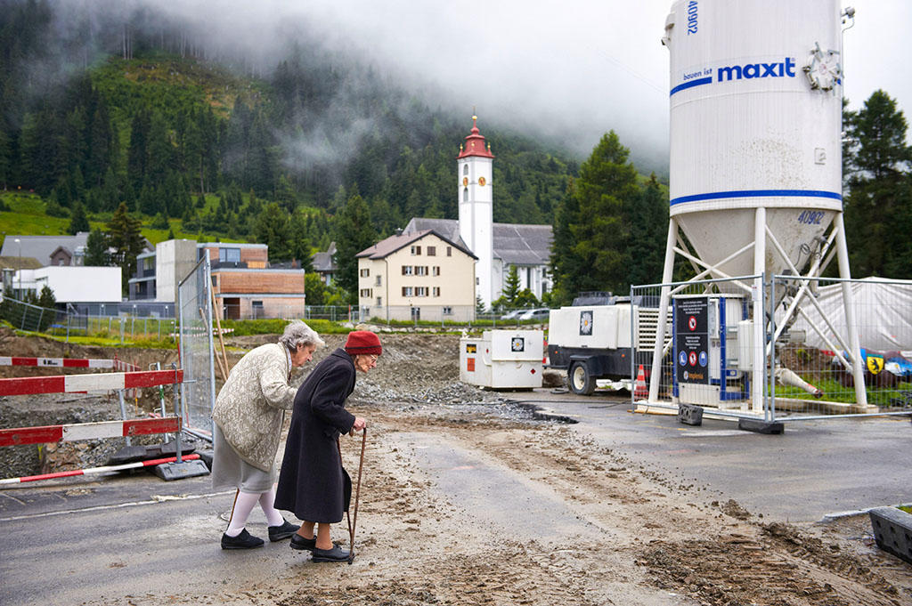 Two elderly women walk through a building site.