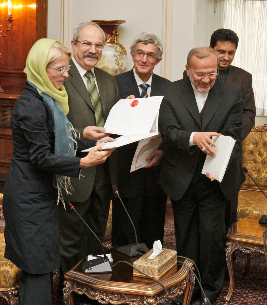 Una mujer y cuatro hombres de pie mirando los papeles de un acuerdo