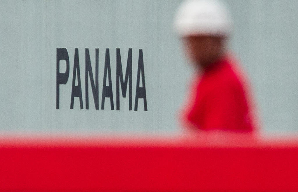 A workman walks by a sign saying Panama