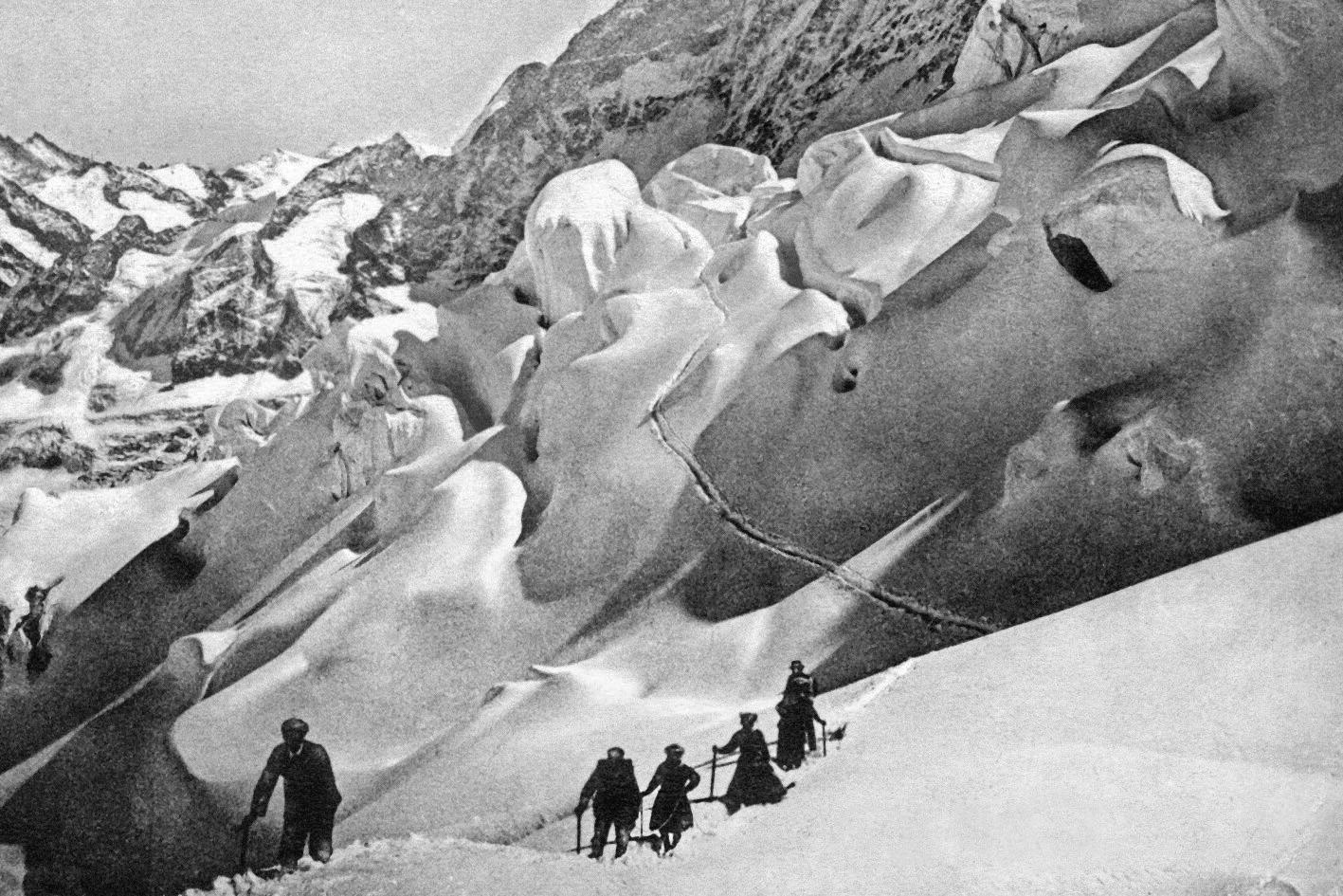 Grupo de personas unidos por una cuerda avanza sobre la nieve, en la montaña