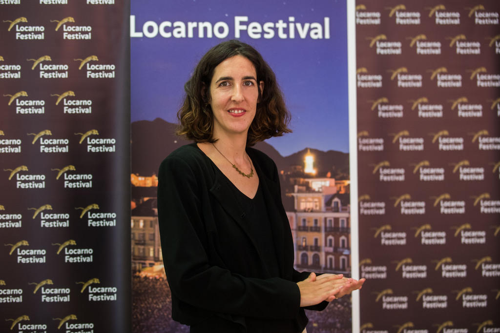 Eine Frau steht vor einem Plakat mit der Aufschrift Locarno Festival und schaut in die Kamera.