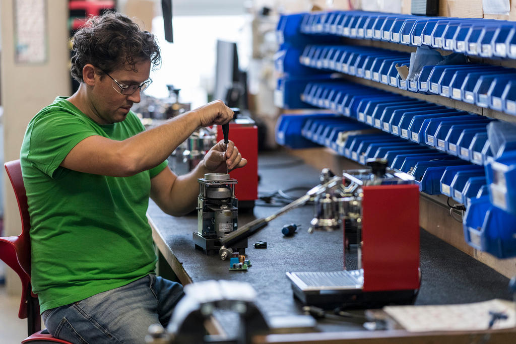 A worker rebuilds a coffee grinder in a factory.