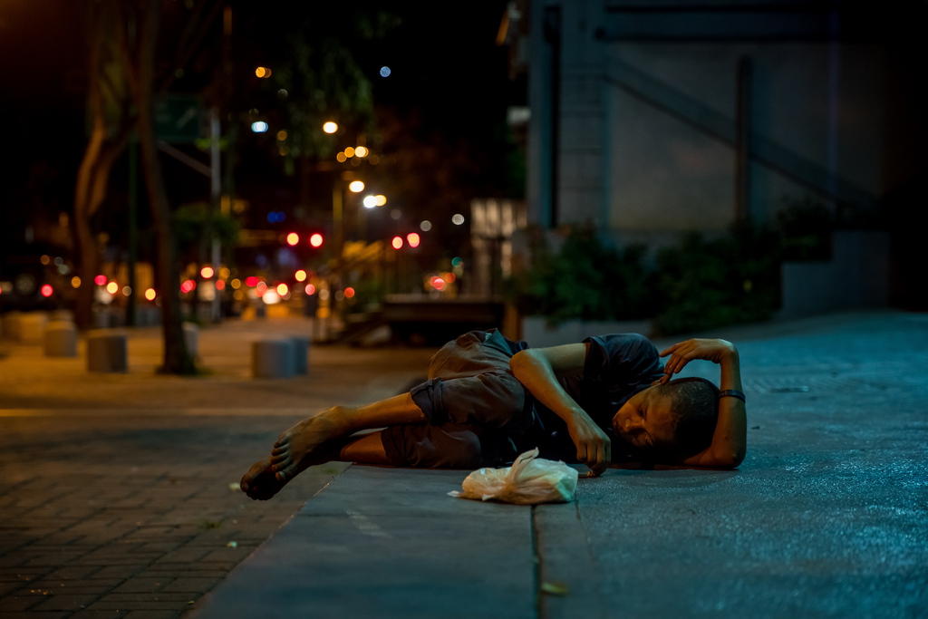 Un bambino dorme sdraiato su un marciapiede, la notte, a Caracas.