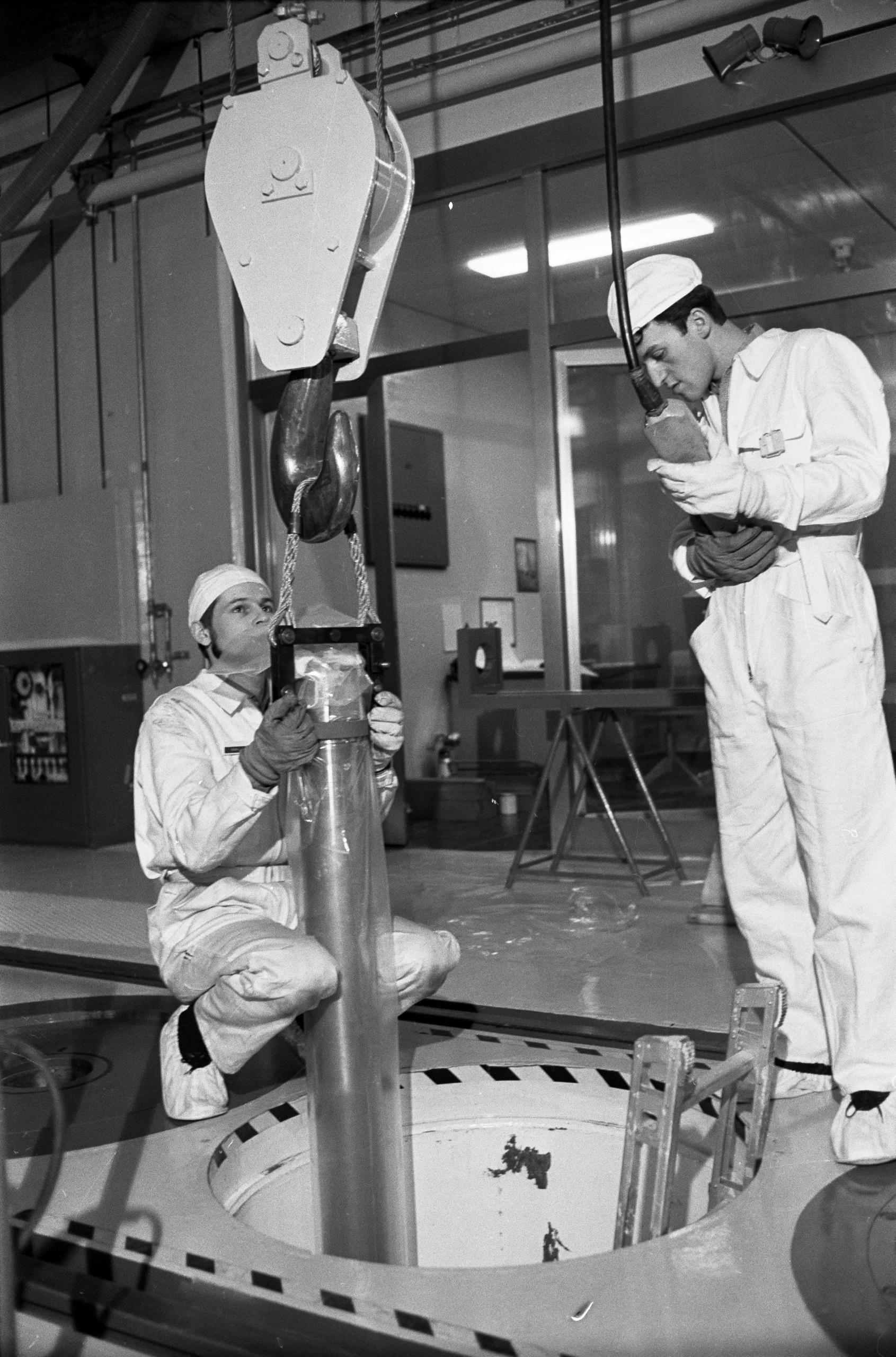 Two men handling fuel rods at a nuclear power plant.