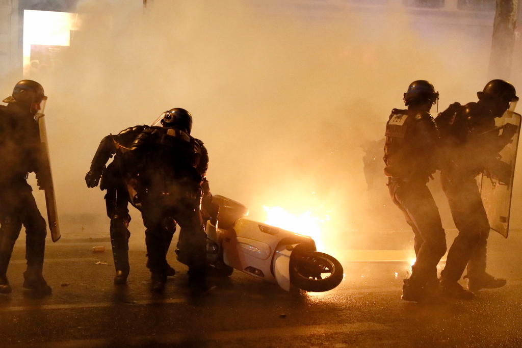 French riot police move a burning scooter from the street