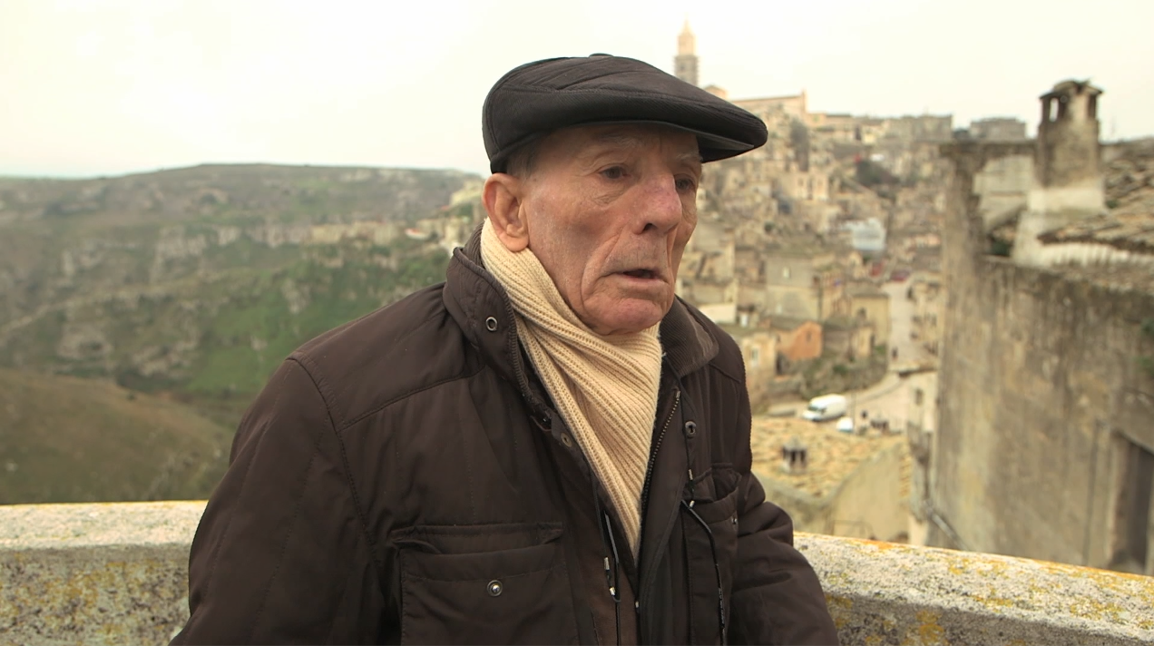 Carlo Vetti, ripreso a parlare con sullo sfondo il qurtiere dei Sassi