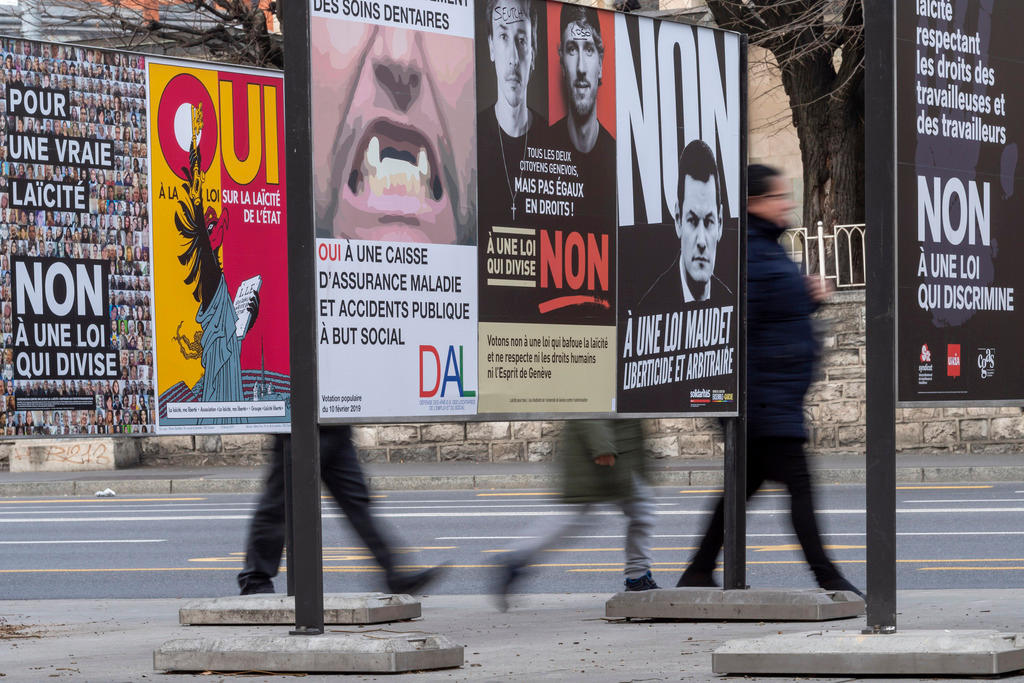 أشخاص يمرون أمام ملصقات في مدينة جنيف