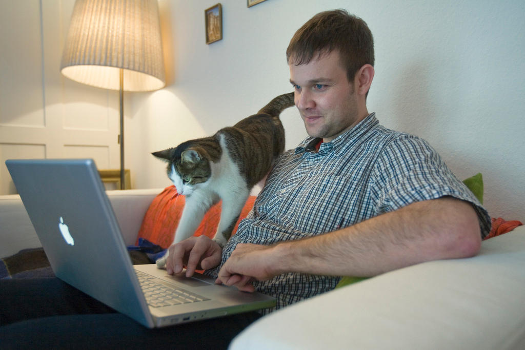 A man looks at his computer with his cat