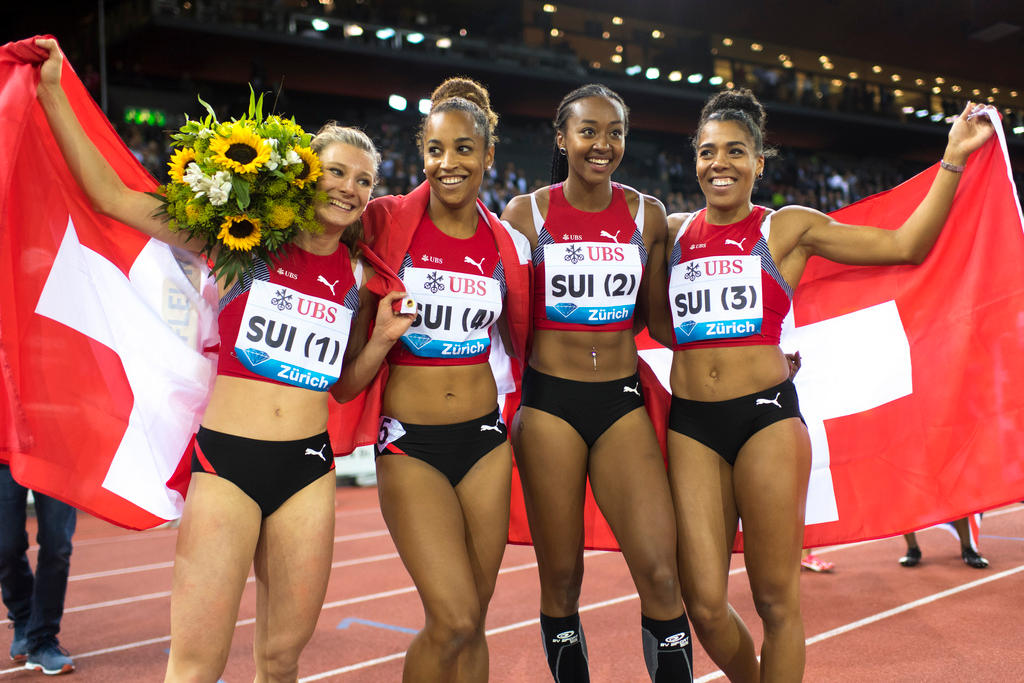 Quatro mulheres atletistas posam com bandeiras e flores