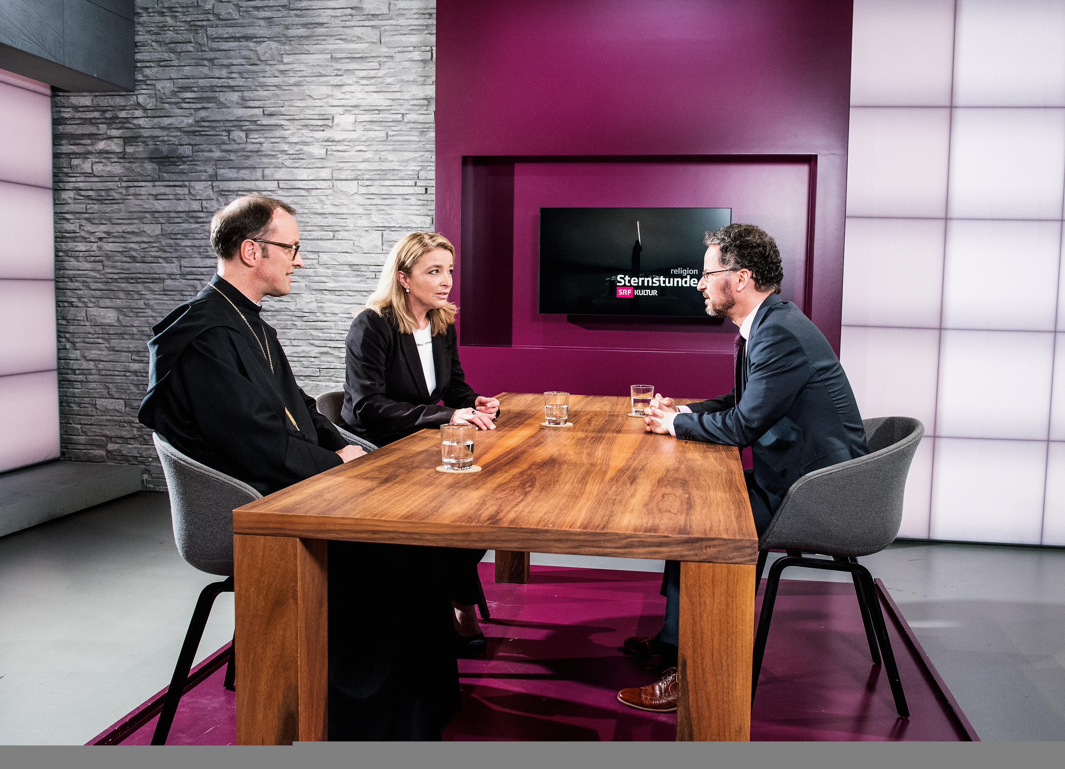 Drei Personen sitzen an einem Tisch.