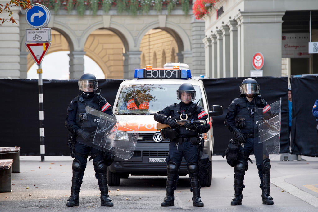 Drei Polizisten in Kampfmontur vor einem Polizeiauto