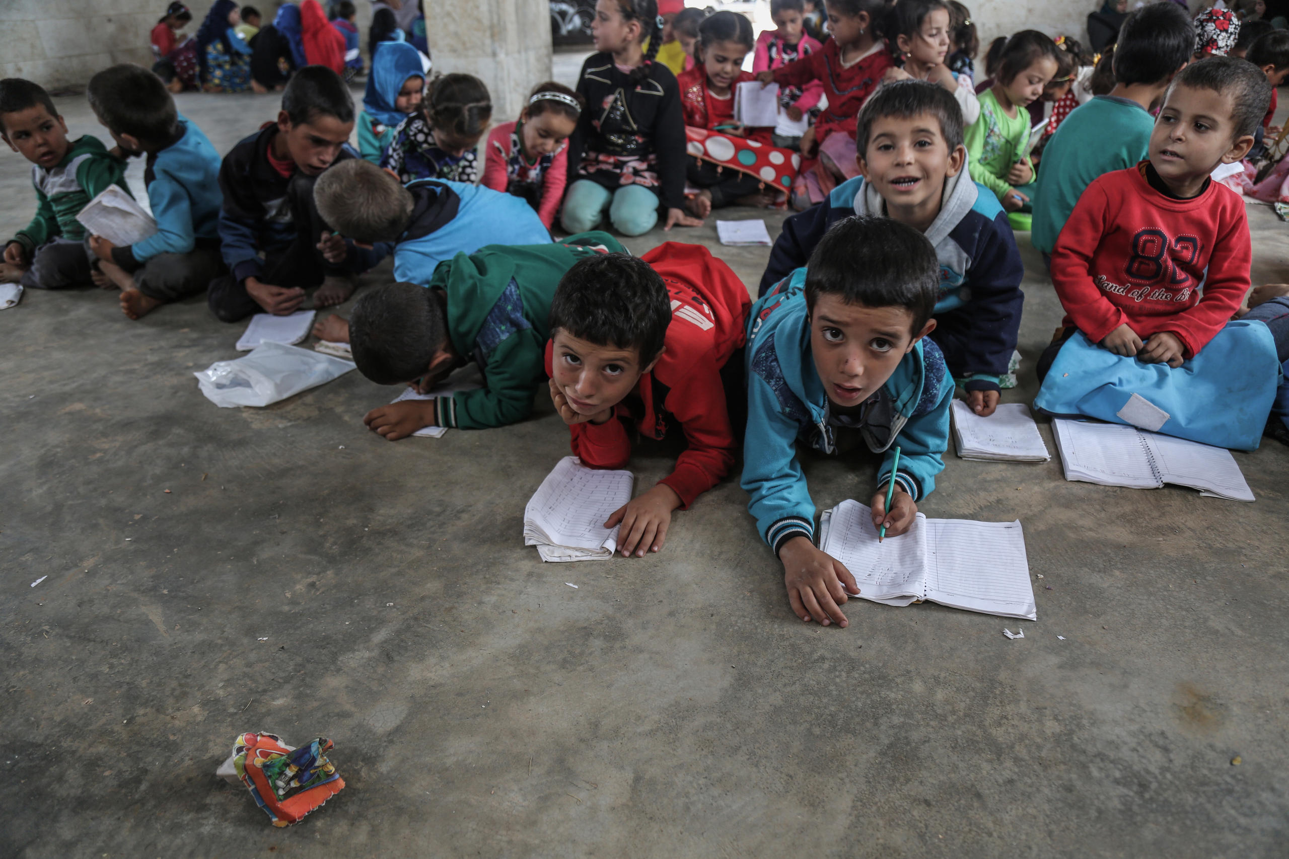 Niños con sus cuadernos sentados en el suelo