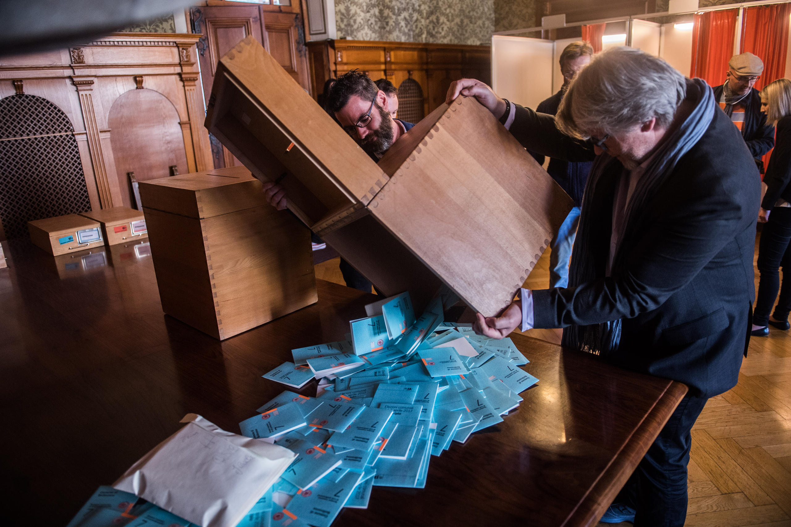 Vote officials emptying a ballot box with blue envelopes