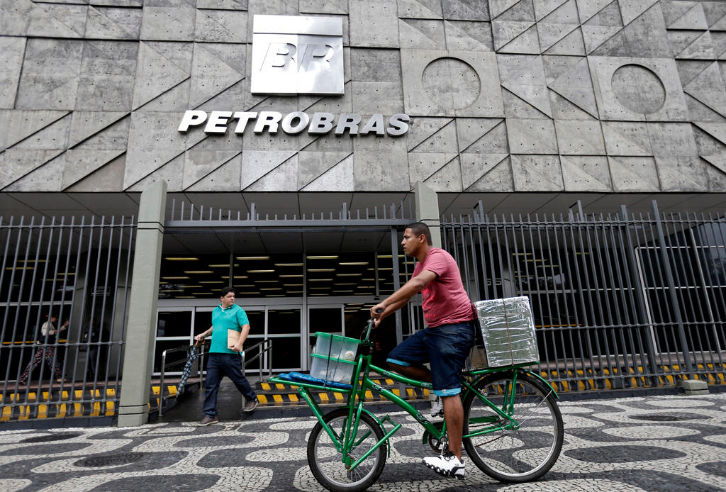 uomo in bicicletta davanti a un edificio della petrobras