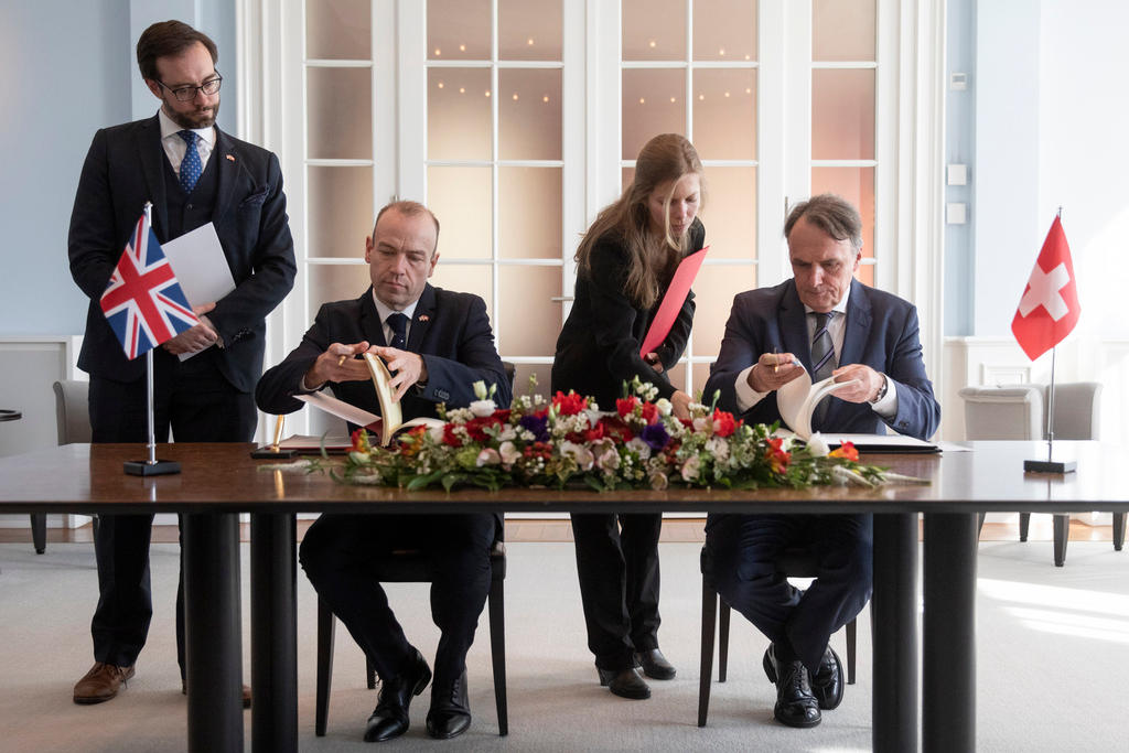 Senior Swiss and British government officials signing an agreement