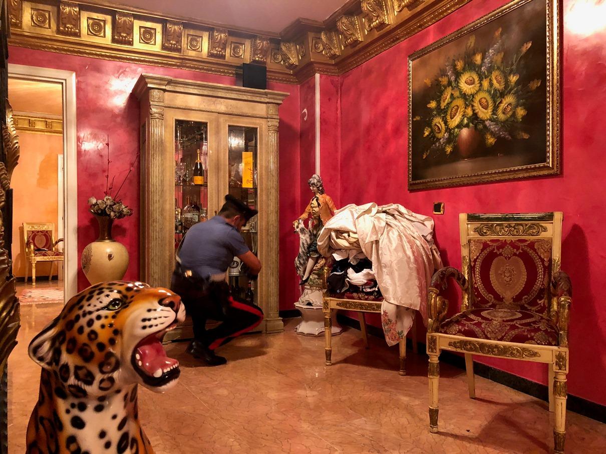 Polizist untersucht Schrank in einer sehr kitschig eingerichteten Villa