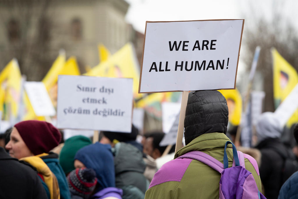 manifestanti innalzano dei cartelli, su uno dei quali si legge we are all human