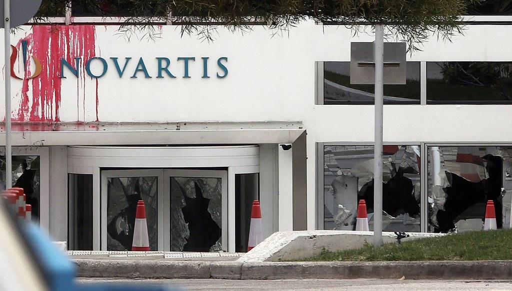Sede de Novartis en Atenas con pintadas y ventanales rotos