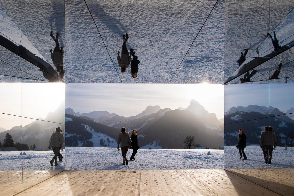 People in shadow walking against a snowy, mountainous backdrop