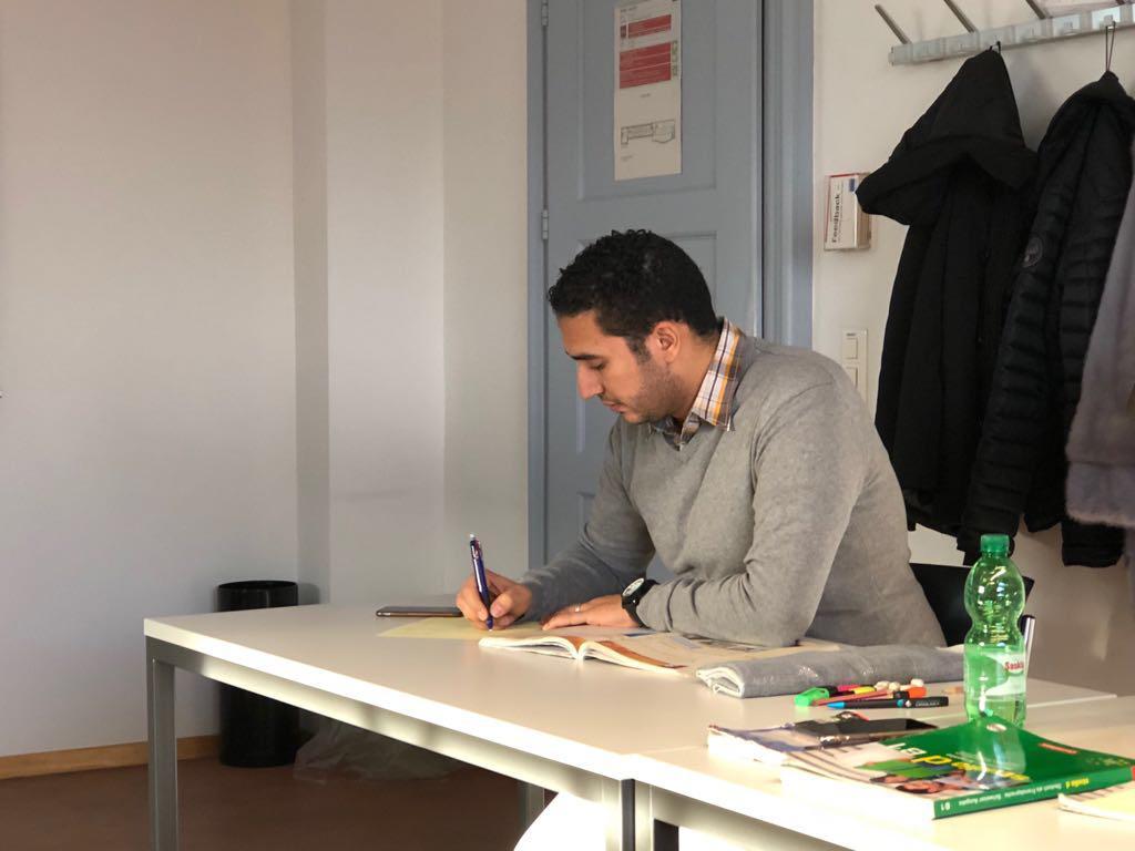 رجل يكتب على منضدة في قاعة تدريس