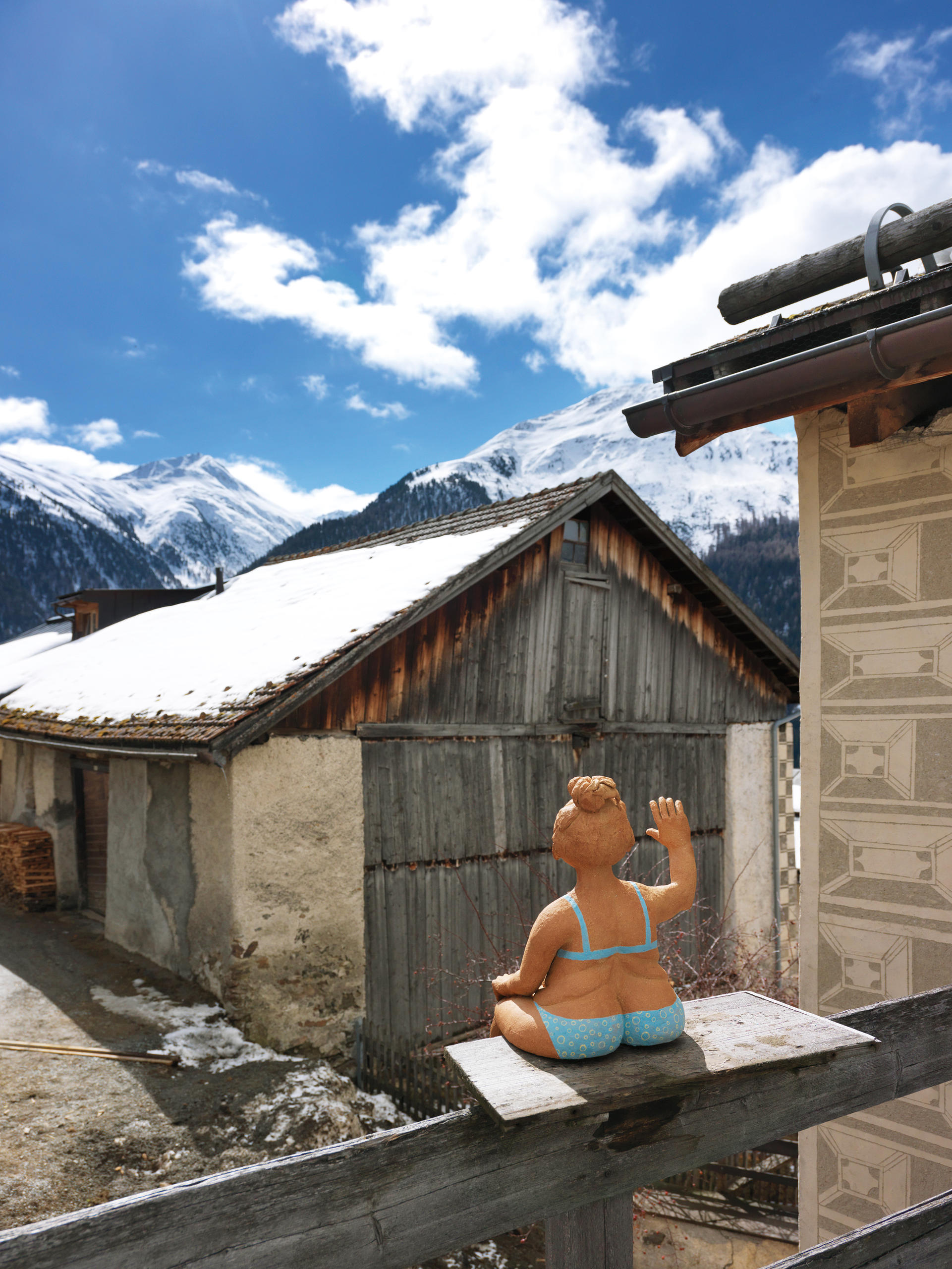 Winkende Kunstfigur von Hinten in sonnigem Dorf