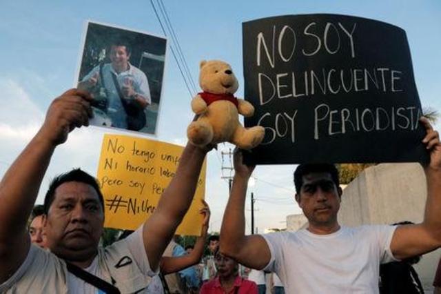 Manifestanti innalzano cartelloni per protestare contro l uccisione di un giornalista in Messico.