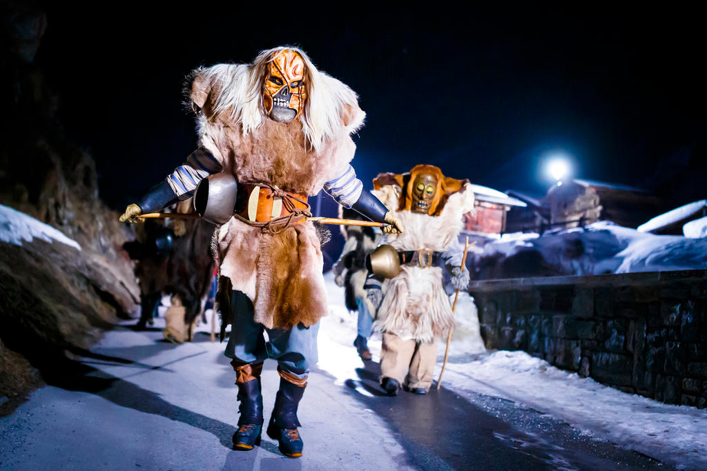 Teilnehmer in Holzmasken und Pelzgewändern am Karneval in den Strassen des Dorfes Blatte