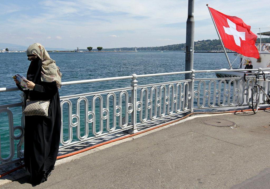 Veiled woman checking mobile phone on Lake Geneva