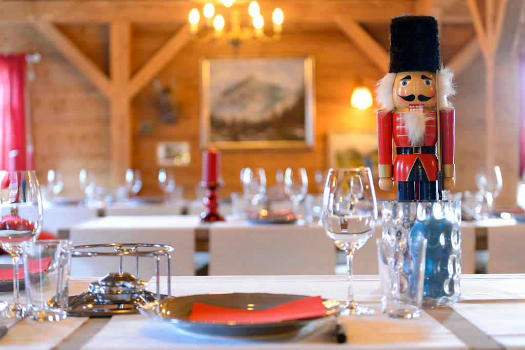 Primo piano di una tavola apparecchiata, con sulla sx un fornellino da fondue e sulla dx piatto, posate, bbicchiere