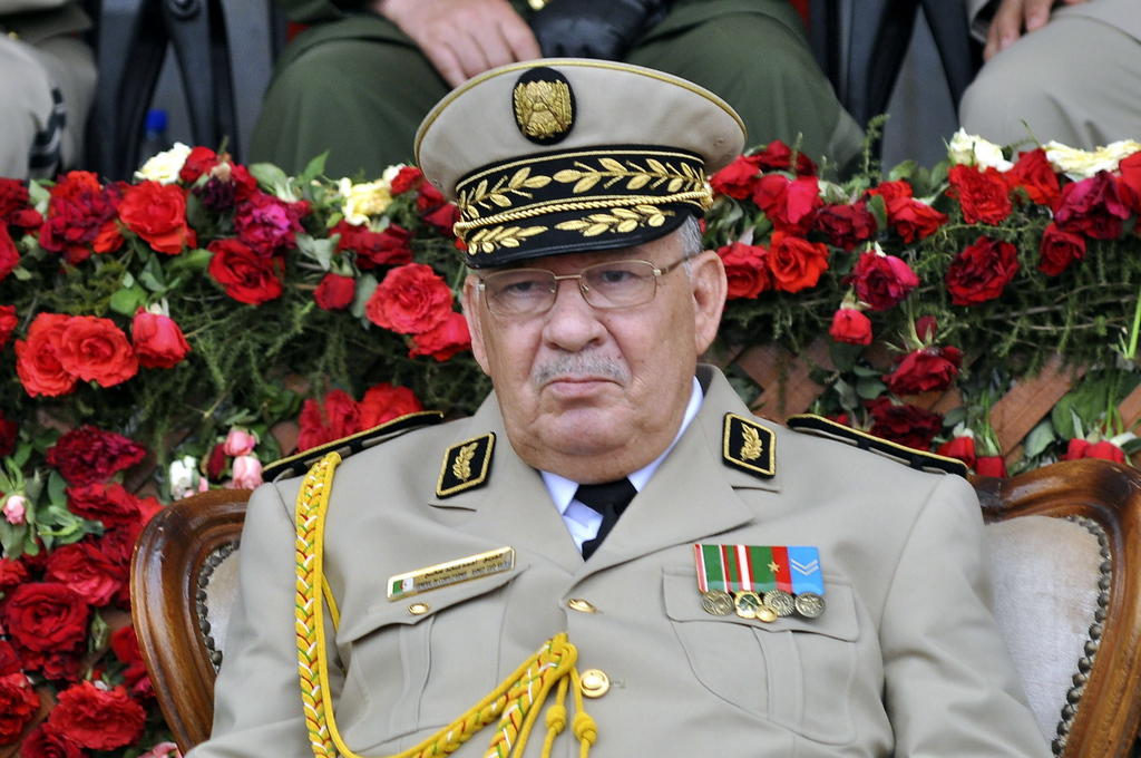 Primo piano di un uomo in uniforme con numerose decorazioni, seduto in una platea decorata da fiori