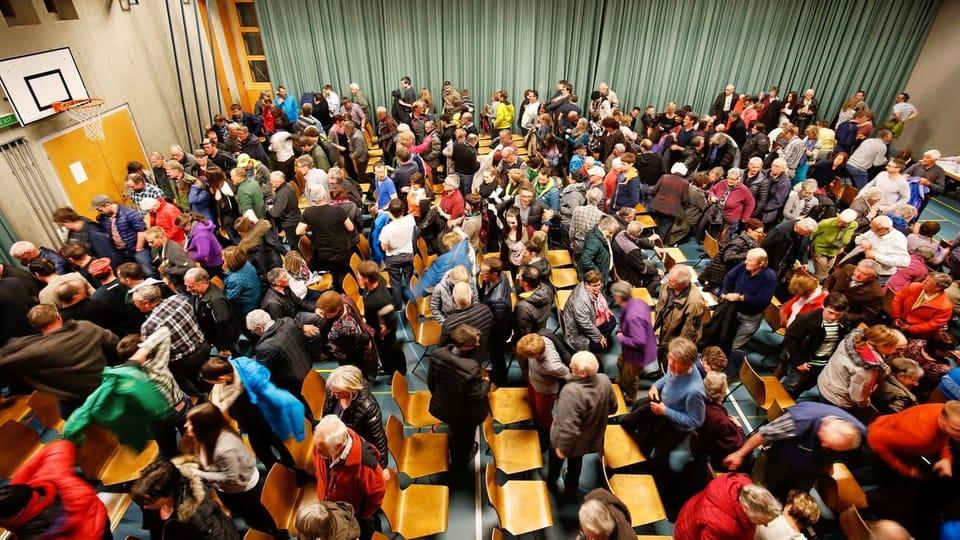 una grande sala piena di gente che si sta alzando dalle sedie.