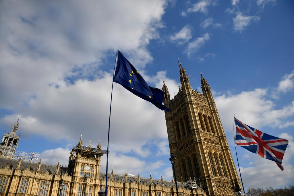 Il Palazzo del parlamento britannico con le bandiere europea e britannica. Dietro un cielo azzurro macchiato da qualche nuvola