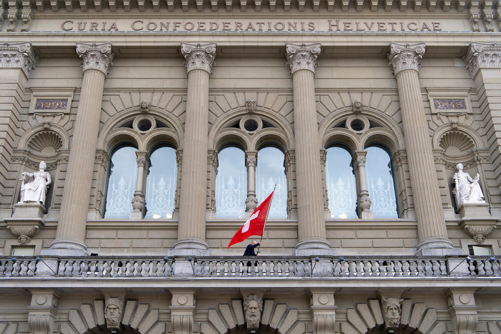 Vista della facciata di Palazzo Federale con vetrate centrali e bandiera svizzera, si intravvedono gli archi dei portali