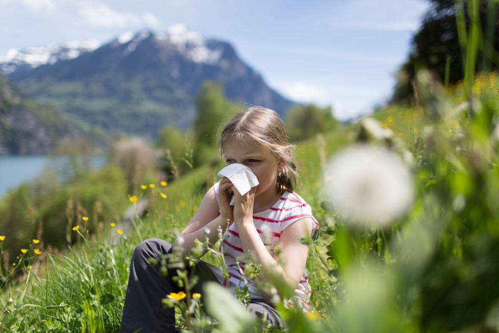 A girl blows her nose in a meadow