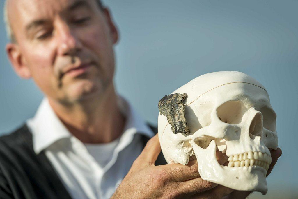 a man holds up skull of homo sapiens