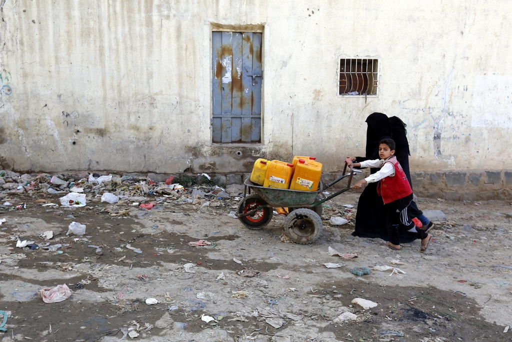 طفل وفتاتان وعربة تحمل أوعية لجمع الماء