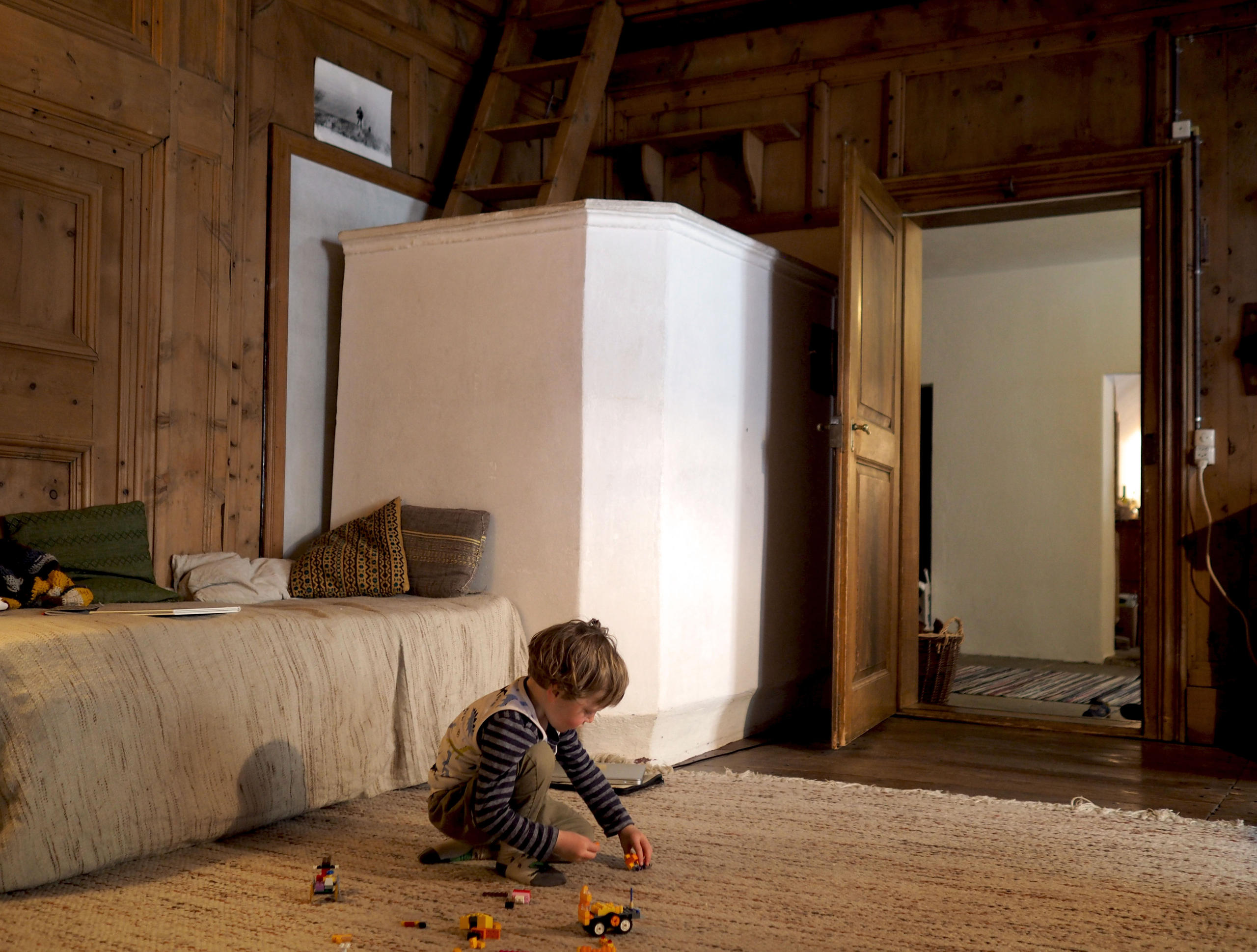 Enfant jouant sur un tapis dans un pièce en bois.