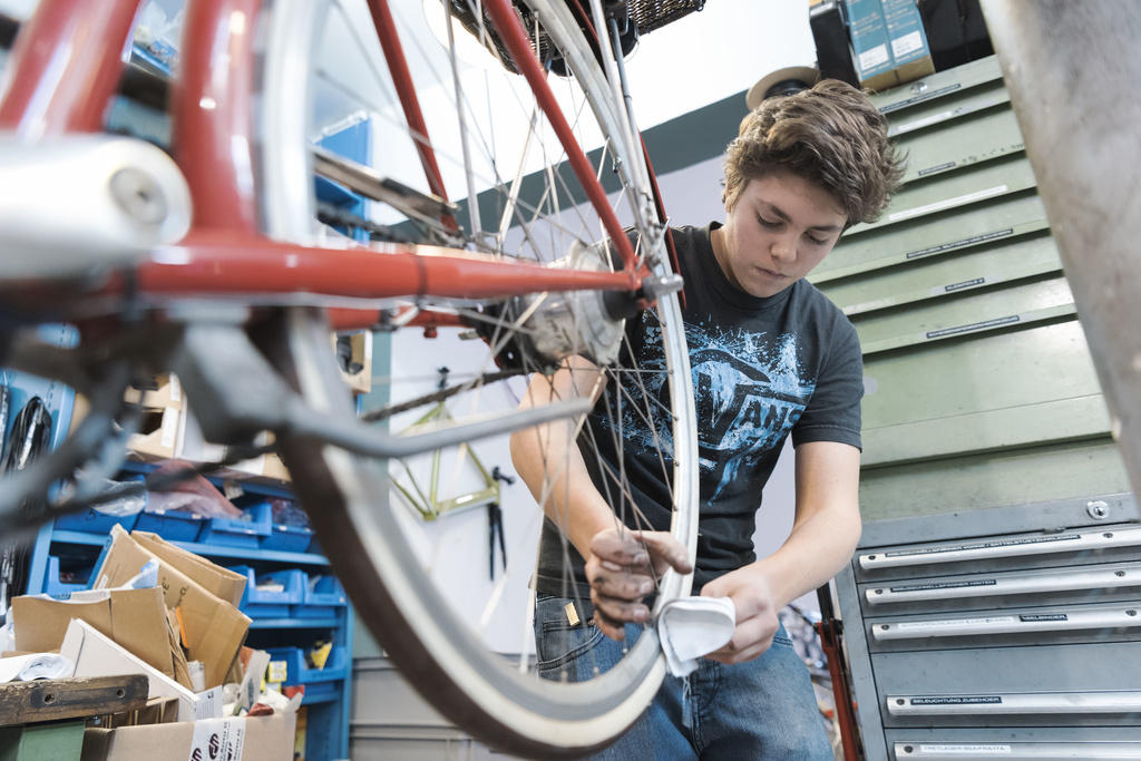早早开始：自行车修理工学徒正在工作。
