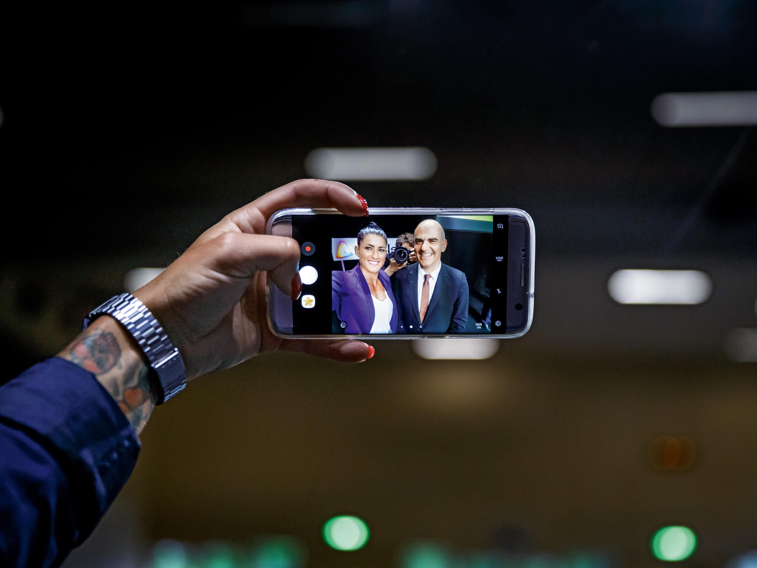 携帯電話でセルフィーを撮影する女性と男性が写る携帯画面