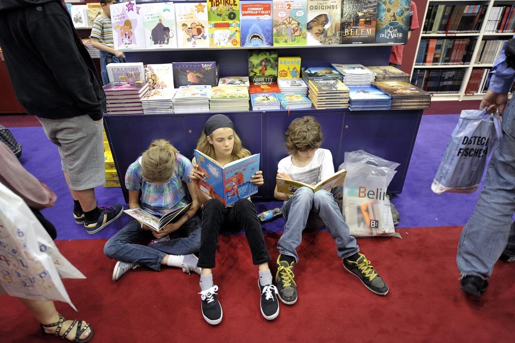 Crianças lendo livros no chão durante o Salão do Livro de Genebra