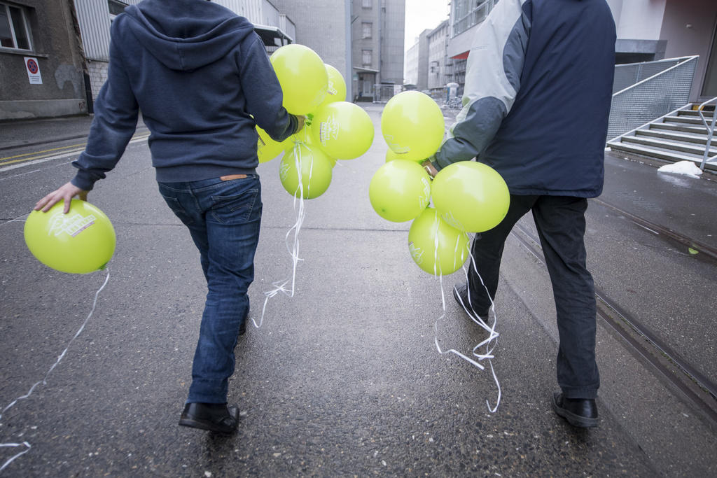 Zwei Personen mit vielen grünen Luftballons von hinten