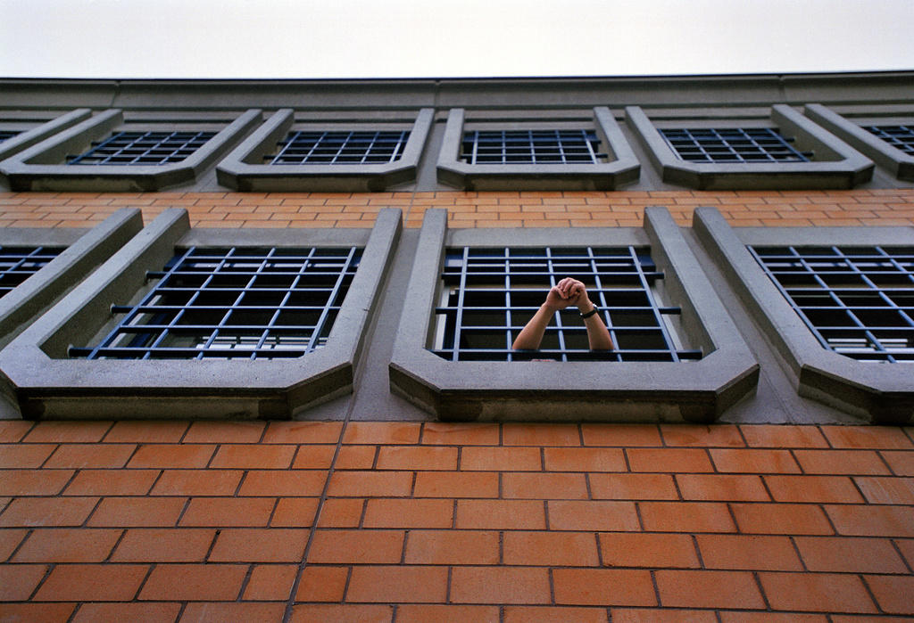 Blick nach oben an eine Hausfassade mit vergitterten Fenstern.
