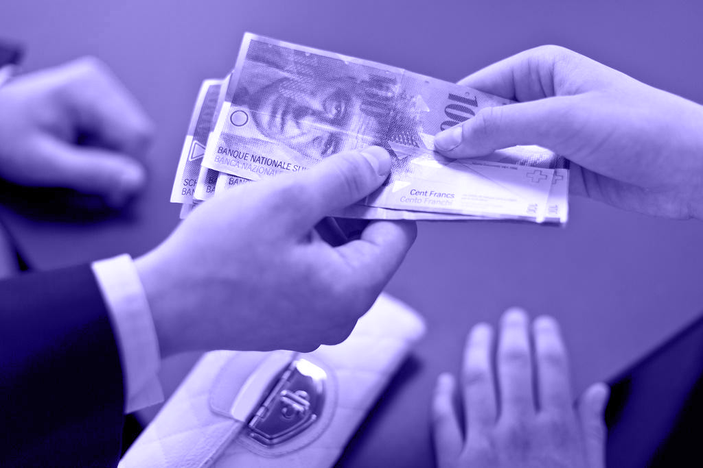 工资 a hand handing wages in 100 swiss franc notes to another hand.