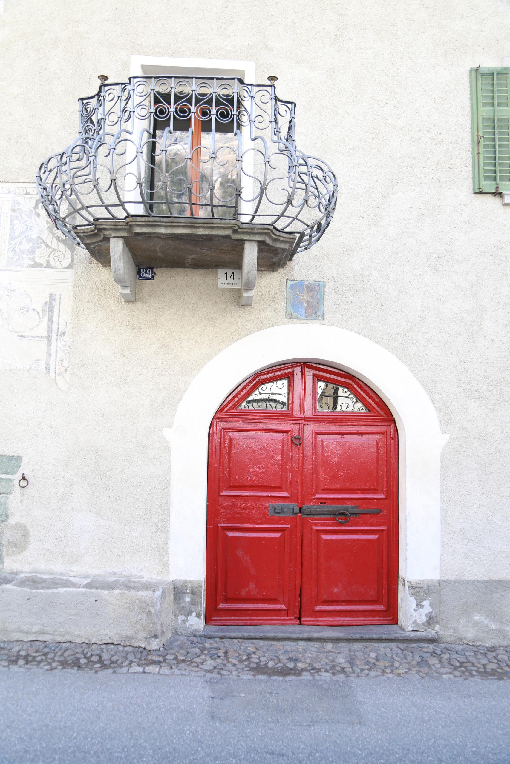 Haustüre, darüber ein Familienwappen, und Balkon