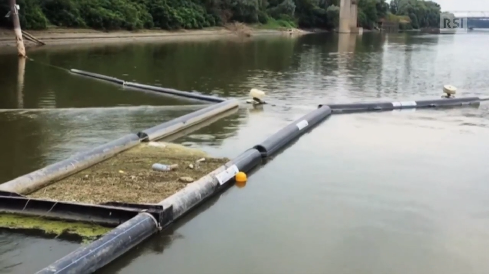 Immagine di un fiume, sul filo dell acqua del quale sono posati dei tubi galleggianti a mo di barriera