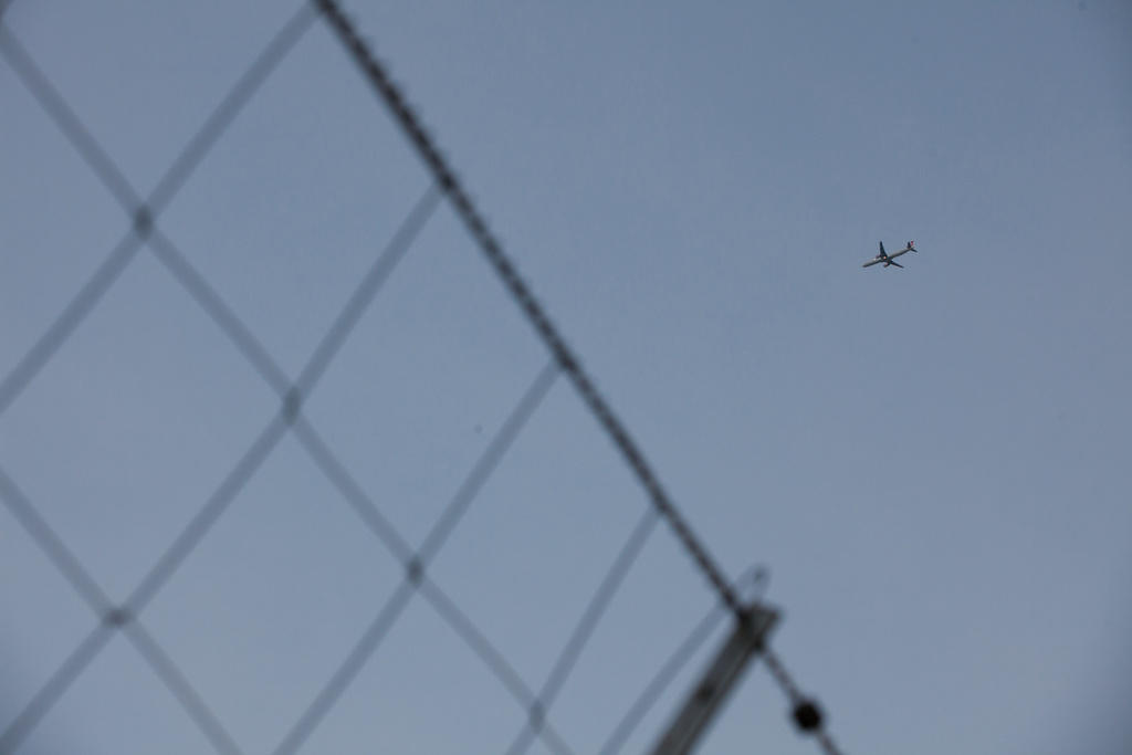 Imagen de un fragmento de valla y un avión en vuelo