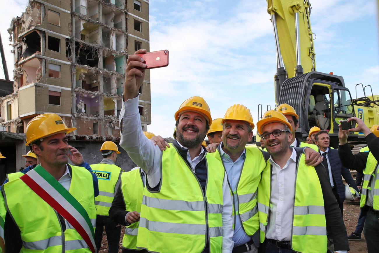 gruppo di persone con gilet e caschi da cantiere si fa un selfie