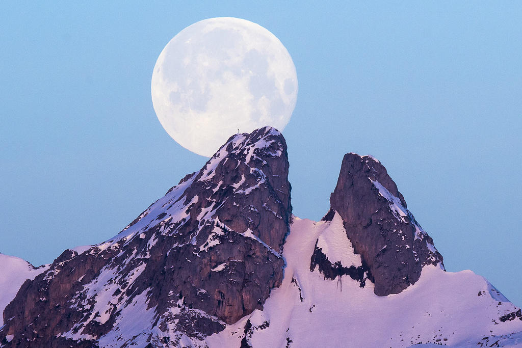Moon appearing behind a mountain