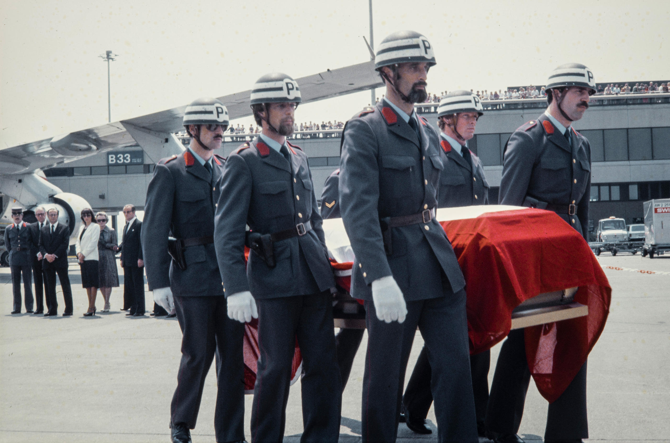 Transport d un cercueil par six policiers casqués.